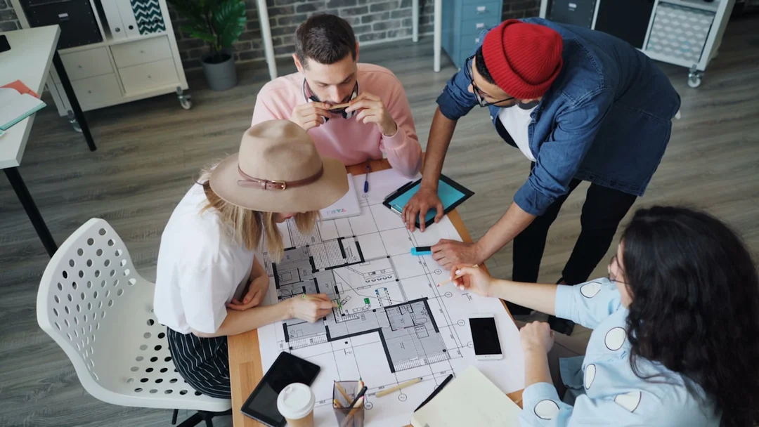 Team of professionals reviewing architectural plans together around a table in a modern office setting