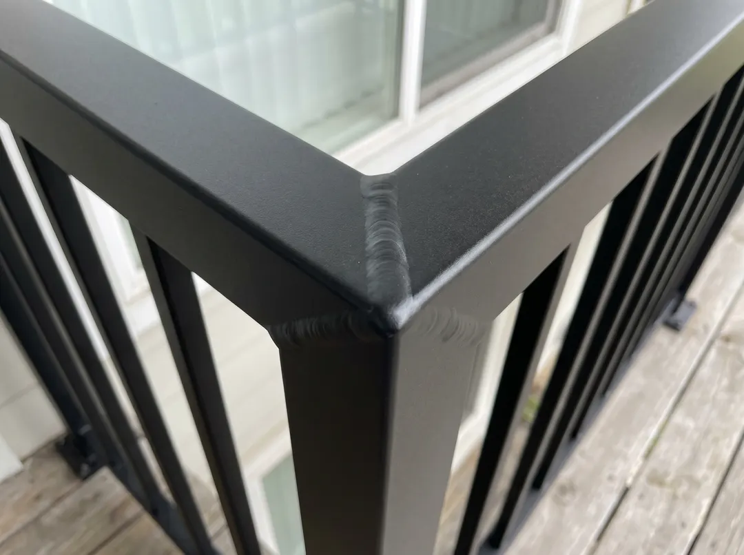 Gros plan d'un joint d'angle soudé sur garde-corps en aluminium peint noir, finition cuite au four
