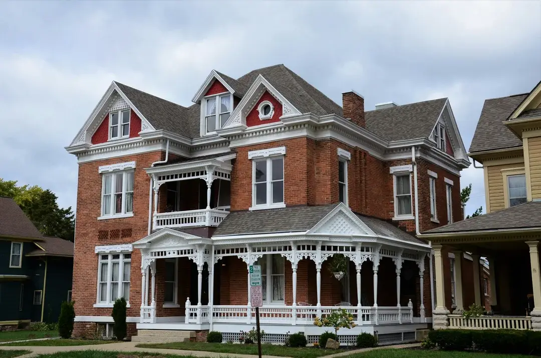 Red brick Victorian house with ornate white wood lacework porch, heritage architecture