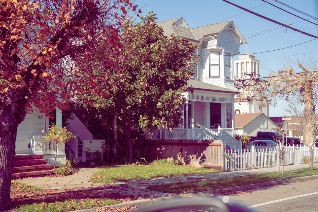 Maison victorienne avec palissade blanche et feuillage d'automne sur une rue résidentielle