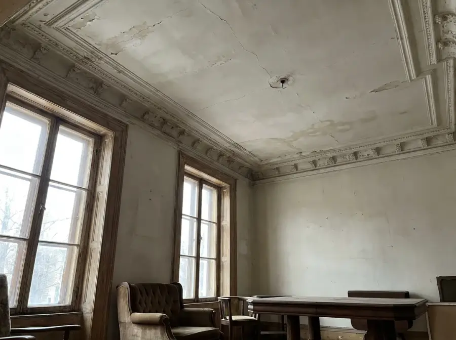 Plafond en plâtre avec corniche, fissures et tache d'infiltration d'eau
