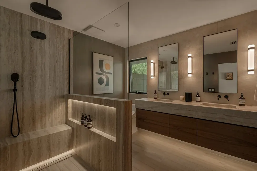 Spa bathroom with stone vanity, walk-in shower, floating cabinets, and warm ambient lighting