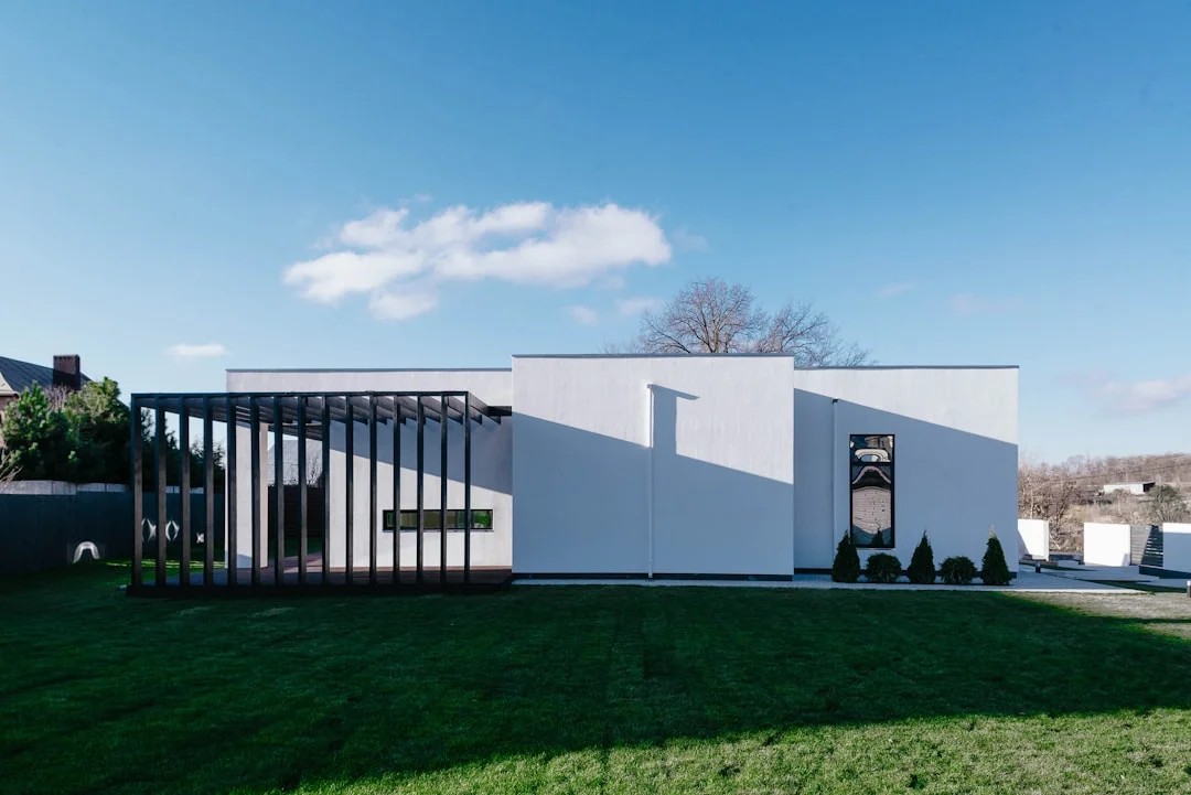 Modern white contemporary house under a spring blue sky with green lawn