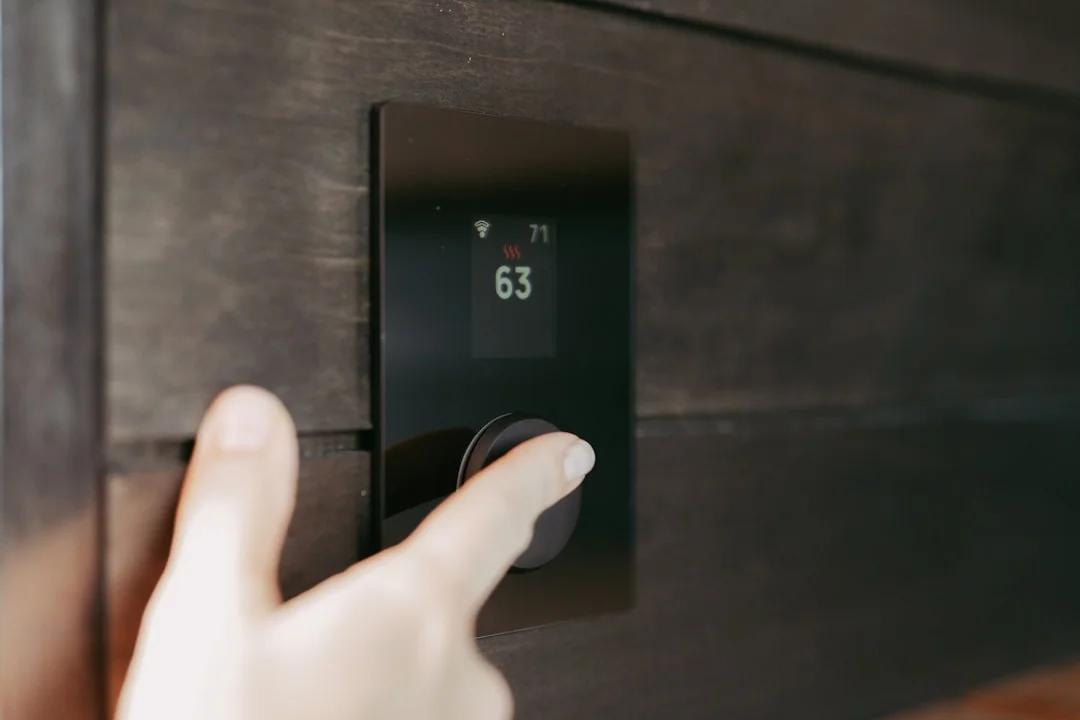 Main ajustant l'affichage d'un thermostat numérique moderne